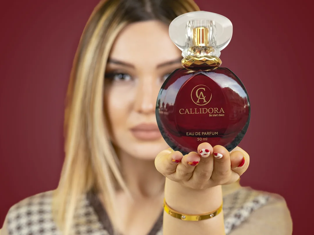 Femme tenant un flacon de parfum Callidora rouge sur fond bordeaux